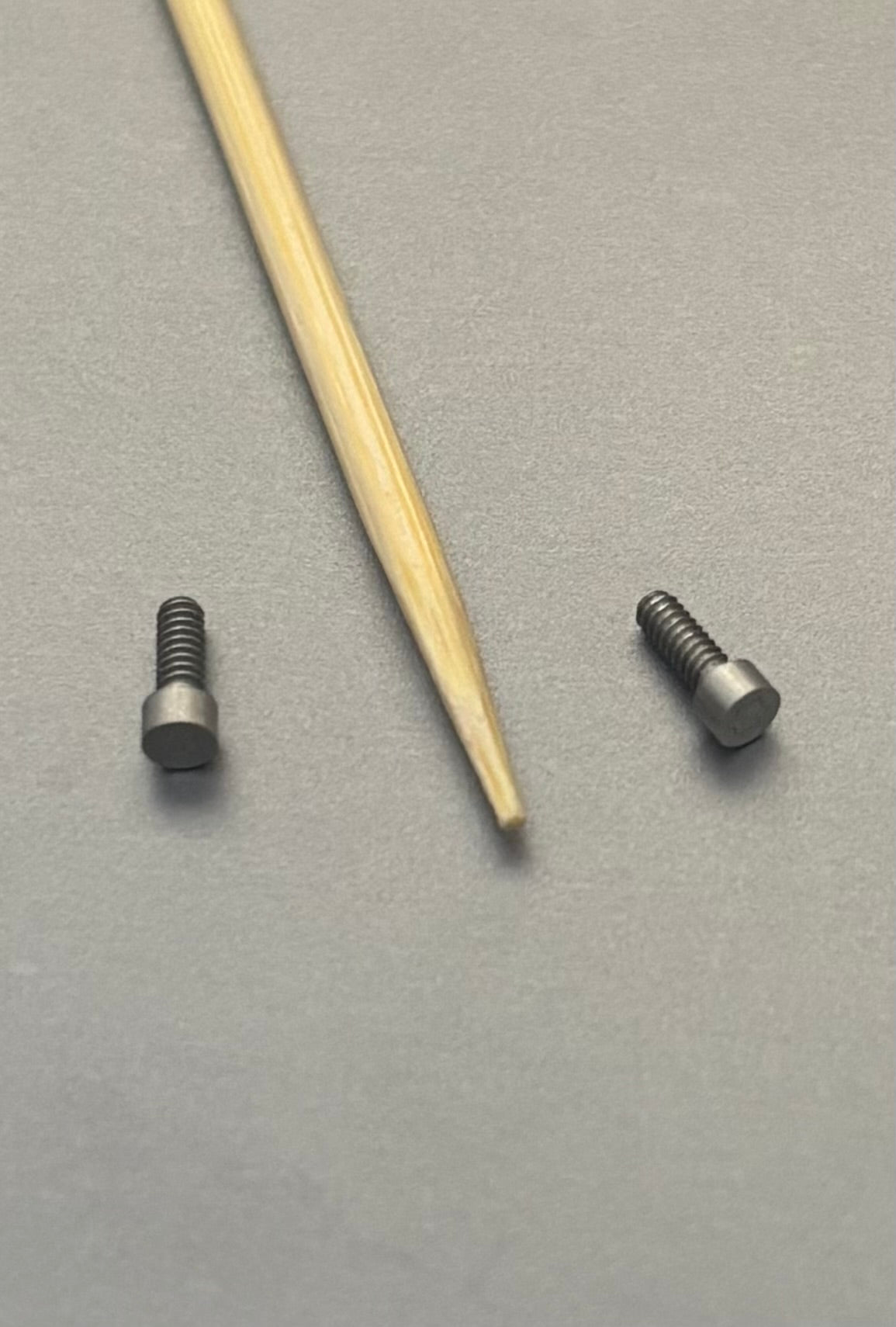 Miniature flush fastener next to a toothpick for scale