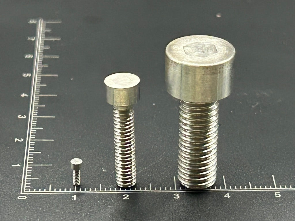 Socket head cap screws at three sizes on a ruler