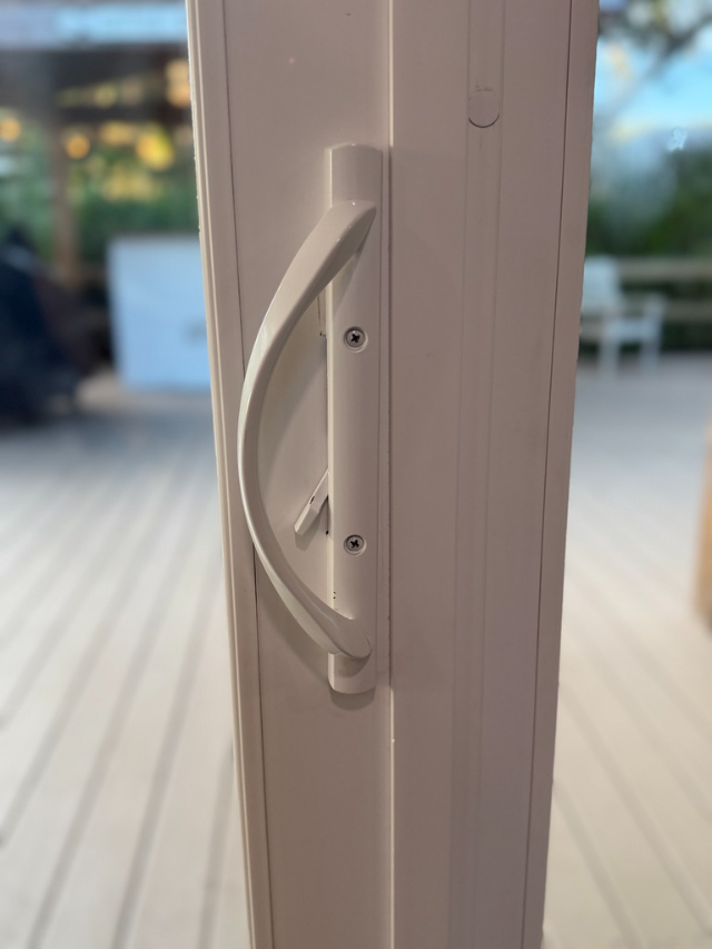 A white patio door handle with two visible screw heads