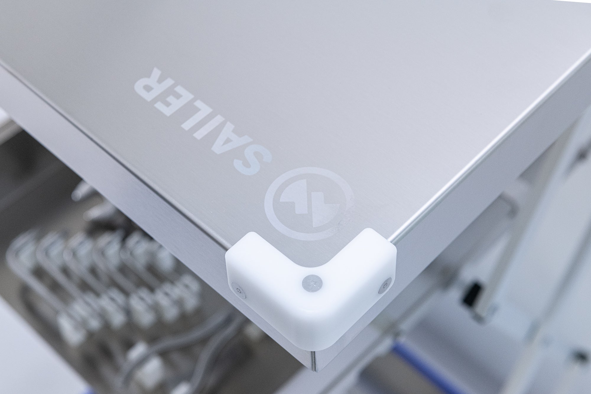 Flush fasteners securing a corner protector on brushed stainless pharma equipment